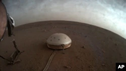 Auf diesem undatierten Foto, das am Donnerstag, den 22. Juli 2021 von der NASA zur Verfügung gestellt wurde, ziehen Wolken über das kuppelbedeckte SEIS-Seismometer des InSight-Landers auf der Marsoberfläche.