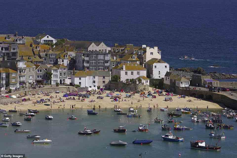 Fishermens' cottages recognisable for their moss-covered roofs crowd around the quaint little harbour in St Ives