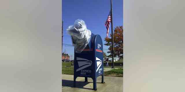 Ein Briefkasten bleibt mit Plastik bedeckt, während eine US-Flagge zu Ehren der beiden Postangestellten in Washington, die am 24. Oktober 2001 in Hamilton, NJ, an Anthrax starben, auf Halbmast weht 