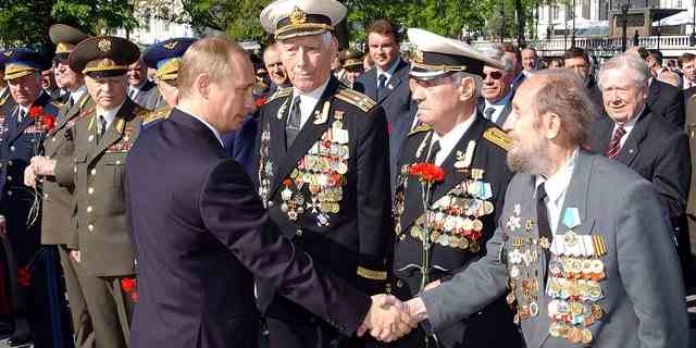Der russische Präsident Wladimir Putin (C) schüttelt Veteranen des Zweiten Weltkriegs nach einer Kranzniederlegung am Grab des unbekannten Soldaten in Moskau am 8. Mai 2002 die Hand. Russland feiert den Tag des Sieges am 9. Mai.