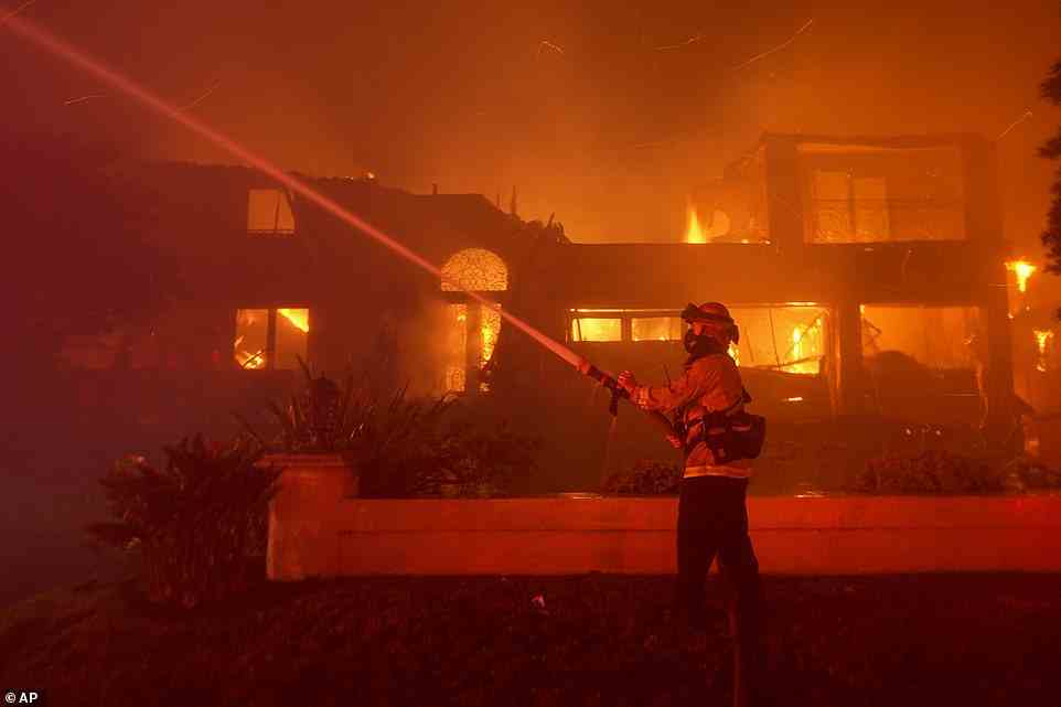 A firefighter on Wednesday night works to put out the blaze in Laguna Niguel, above Laguna Beach