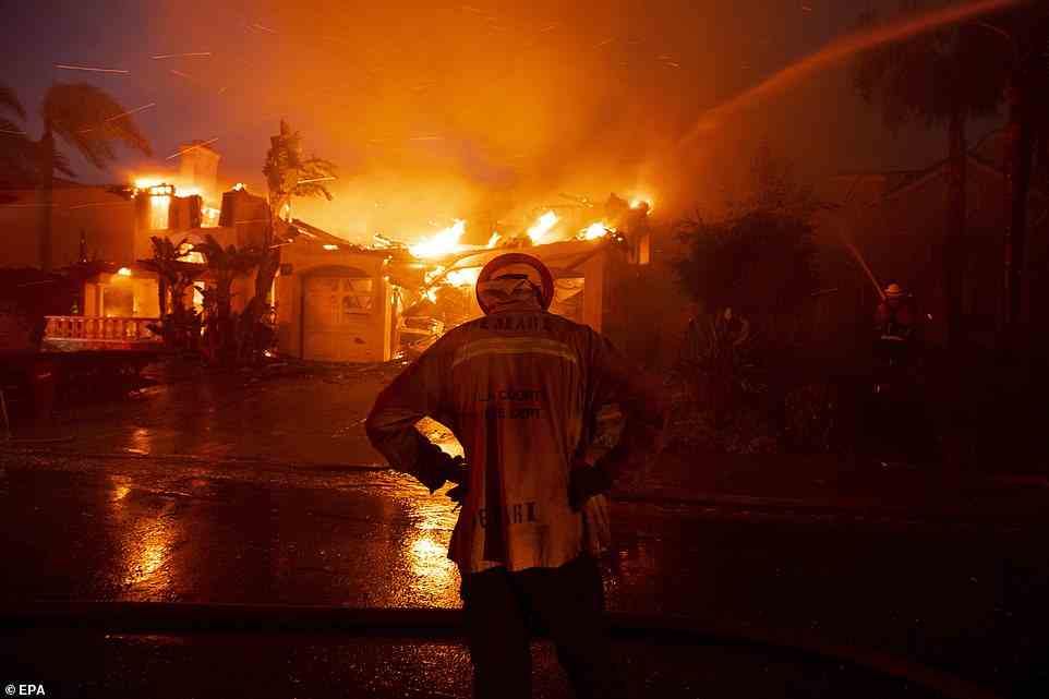 A firefighter puts his hands on his hips and dips his head at the sheer scale of the wildfire which has destroyed dozens of houses in Laguna Niguel on Wednesday