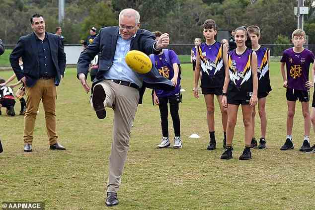 Herr Morrison versucht während seines Auftritts am Samstagmorgen in Victoria einen Drop Punt, um eine Schulsportinitiative anzukündigen