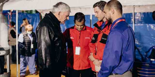 Rev. Graham (links) wird gezeigt, wie er mit einem Team vor Ort in der Ukraine betet.