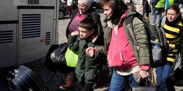 Ukrainische Flüchtlinge mit Kindern steigen am Dienstag, 22. März 2022, auf einem Platz neben einem Bahnhof in Przemysl, Polen, in ein Transportmittel ein. 