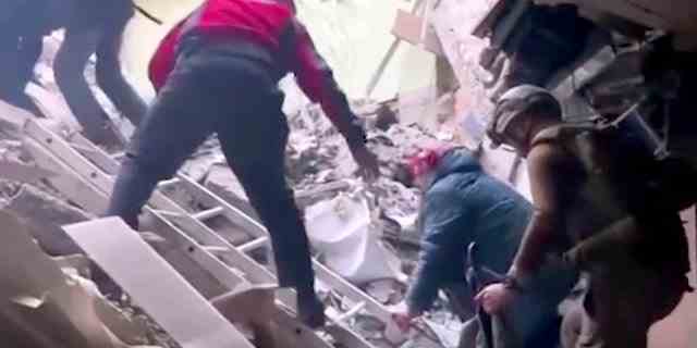 Dieses Bild aus einem undatierten Video, das am Sonntag, dem 1. Mai, vom Asowschen Spezialeinheitsregiment der ukrainischen Nationalgarde zur Verfügung gestellt wurde, zeigt Menschen, die über Trümmer des Stahlwerks Asowstal in Mariupol in der Ostukraine klettern. 
