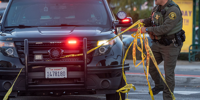 Der Stellvertreter eines Sheriffs aus Orange County entfernt am Sonntag, den 15. Mai 2022, nach einer tödlichen Schießerei gelbes Klebeband von einem Fahrzeug vor der Geneva Presbyterian Church in Laguna Woods, Kalifornien. 