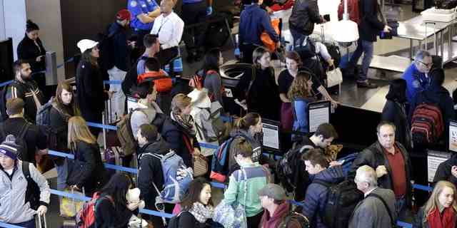 Reisende stellen sich an einer Sicherheitskontrolle am O'Hare International Airport an.