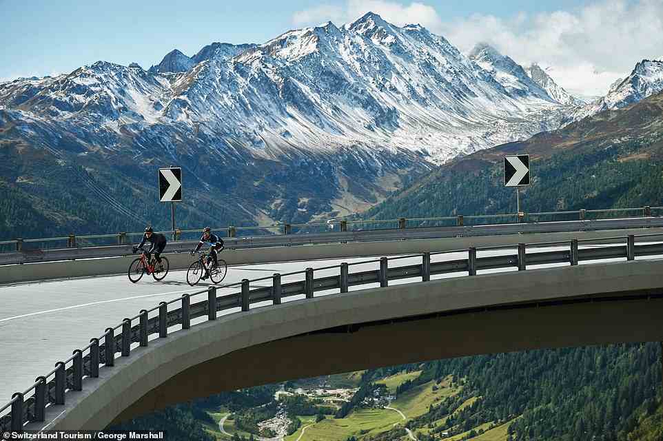Two cyclists cruise around a hairpin bridge on the Gotthard Pass main road (aka 'National Road 2') above Airolo. This route runs next to the old Tremola road