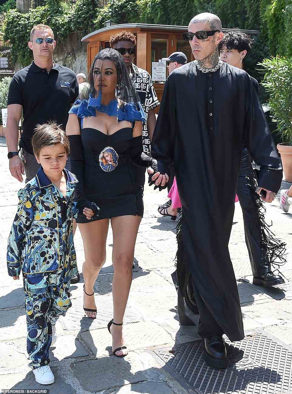 Bride to be: Kourtney donned a black sheer veil with blue lace detail and Travis wore a full-length gown as the pair strolled with Reign