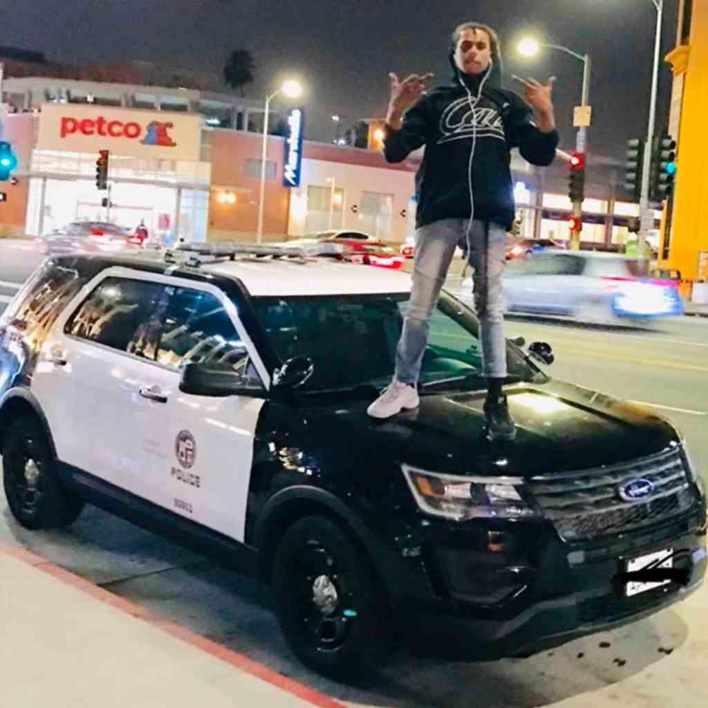 Isaiah Lee, alias Rapper Noname Trapper," ist auf einem Youtube-Foto zu seinem Song zu sehen "David Chappell." Er steht auf einem Polizeiauto, in Jeans, Hoodie und Turnschuhen, die nicht zusammenpassen.