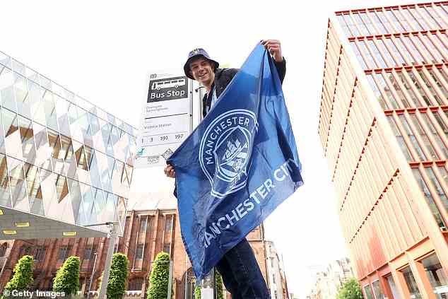 Ein Fan von Manchester City klettert auf eine Bushaltestelle, um den besten Blick auf die Busparade zu haben
