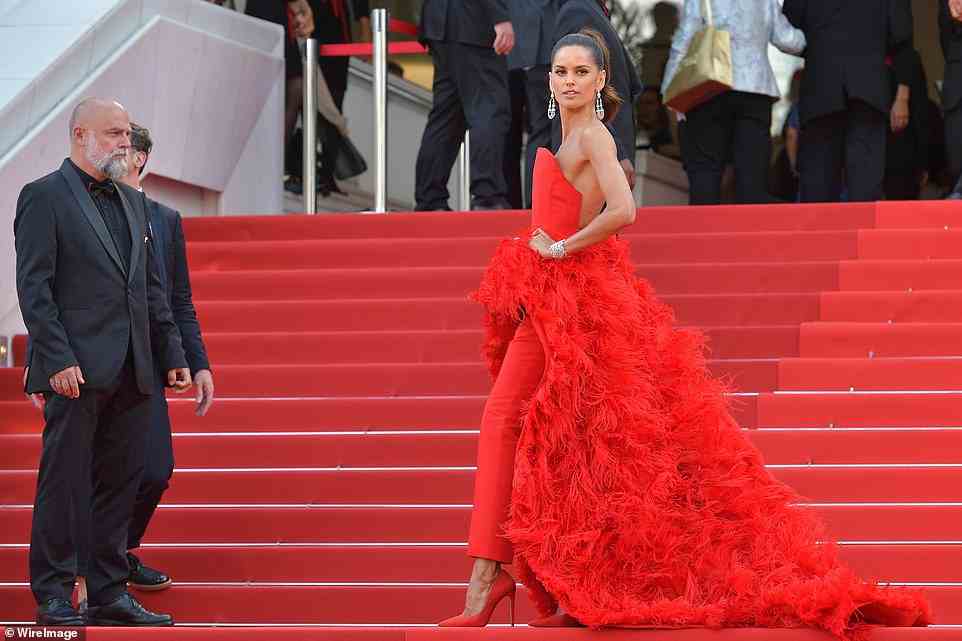 Trendy: Izabel Goulart wowed in a bright red gown with a full feathered skirt, which she teamed with bold red trousers and matching heels