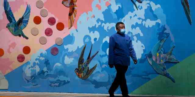 Ein Mann mit Gesichtsmaske geht an einem Wandgemälde entlang einer Straße in Peking vorbei, Mittwoch, 25. Mai 2022. 