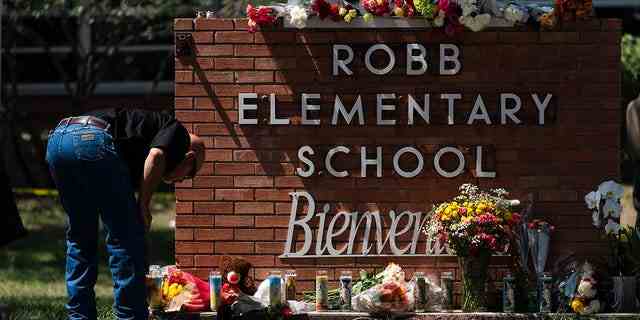 Ein Mitarbeiter der Strafverfolgungsbehörde zündet am Mittwoch, den 25. Mai 2022, eine Kerze vor der Robb Elementary School in Uvalde, Texas, an.