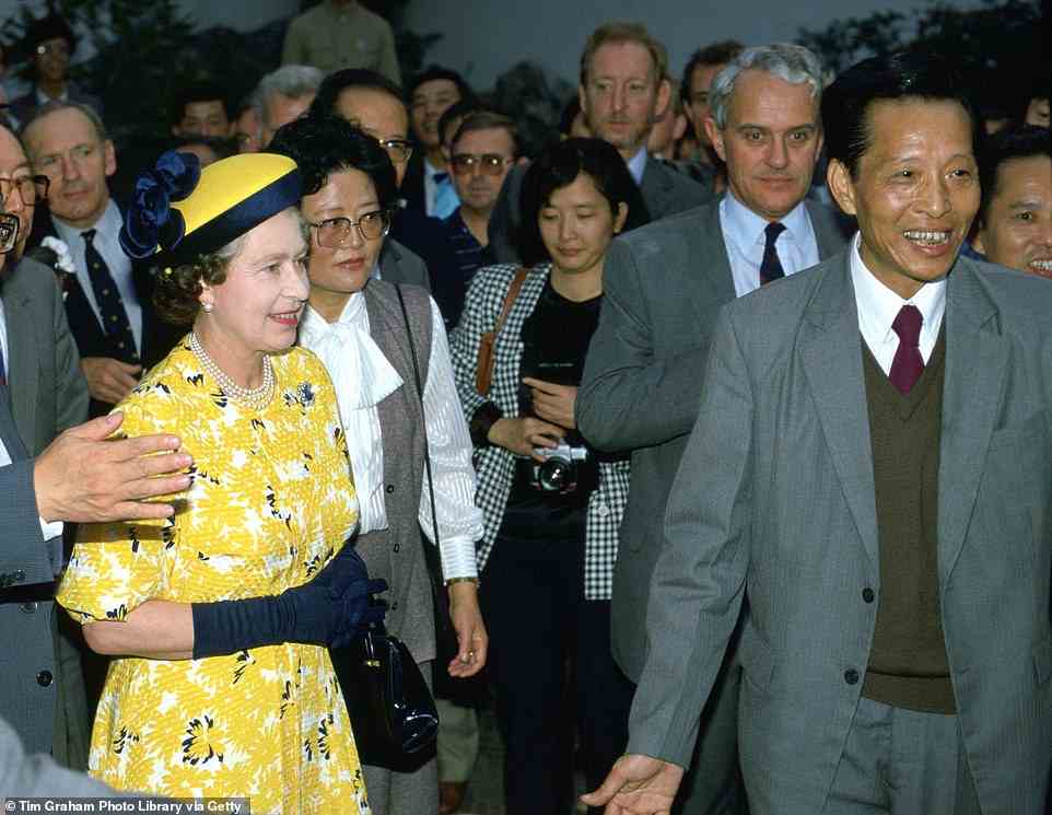 The Queen in Shanghai on October 15, 1986, with Michael Shea, her press secretary (grey hair on the right), accompanying her. The yellow-and-blue dress with matching hat was by fashion designer Ian Thomas