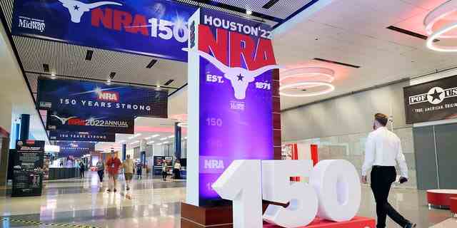 Auf der NRA-Jahrestagung, die am Donnerstag, den 26. Mai 2022, im George R. Brown Convention Center in Houston stattfand, gehen Menschen an Beschilderungen in den Gängen außerhalb der Ausstellungshallen vorbei.  (AP Foto/Michael Wyke)