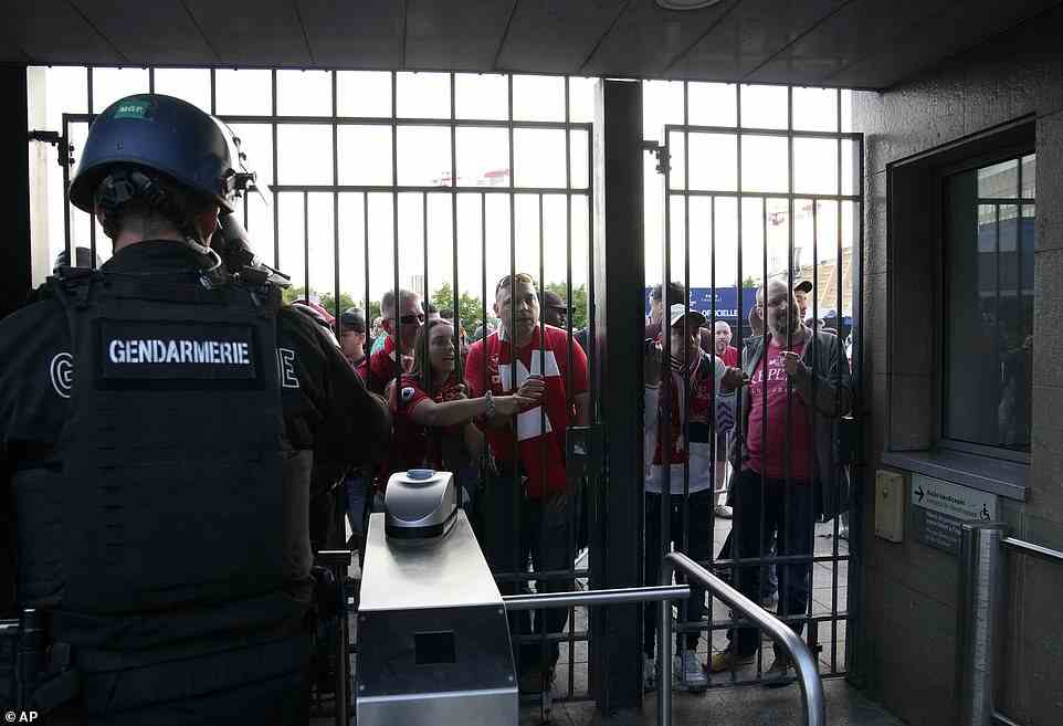 Liverpool fans grasp onto the gates of the Stade de France as they wait outside the venue as kickoff was delayed