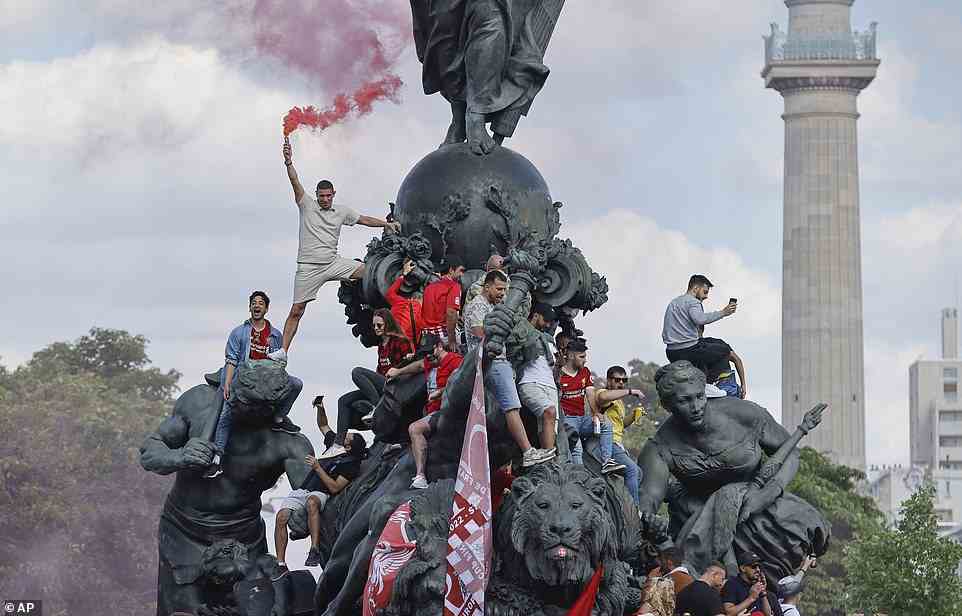 A group of Liverpool fans set off flares and hang flags atop a statue in Paris ahead of the UEFA Champions League final