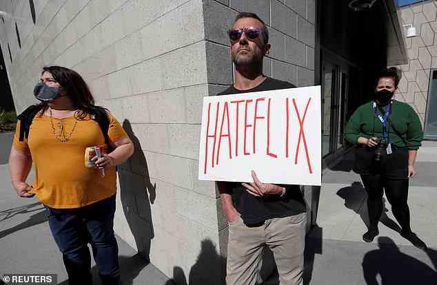 The stand-up special aired just one week after Netflix changed its guidance asserting that executives will not 'censor specific artists or voices' even if employees consider the content 'harmful.' A staff member Dave Briggs is seen here holding a placard as he attends a rally in support of the Netflix transgender employee walkout in October