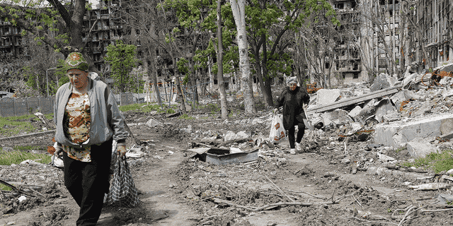 Frauen gehen am Montag, dem 2. Mai, an einem zerstörten Wohnhaus in Mariupol vorbei, das sich auf dem Gebiet der Regierung der Volksrepublik Donezk befindet.