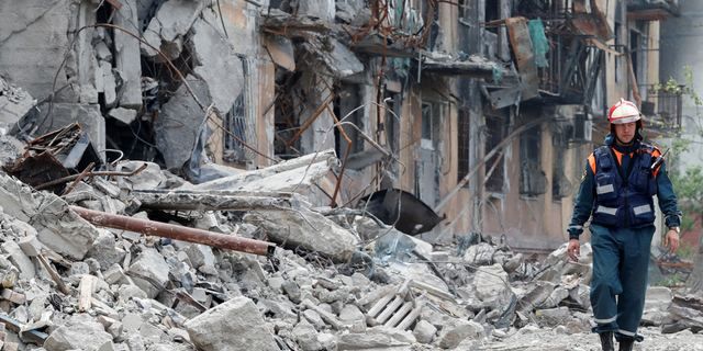 Ein Mitglied des russischen Katastrophenschutzministeriums geht am Donnerstag, den 11. Mai, in der Nähe eines zerstörten Wohngebäudes in Mariupol, Ukraine, vorbei.