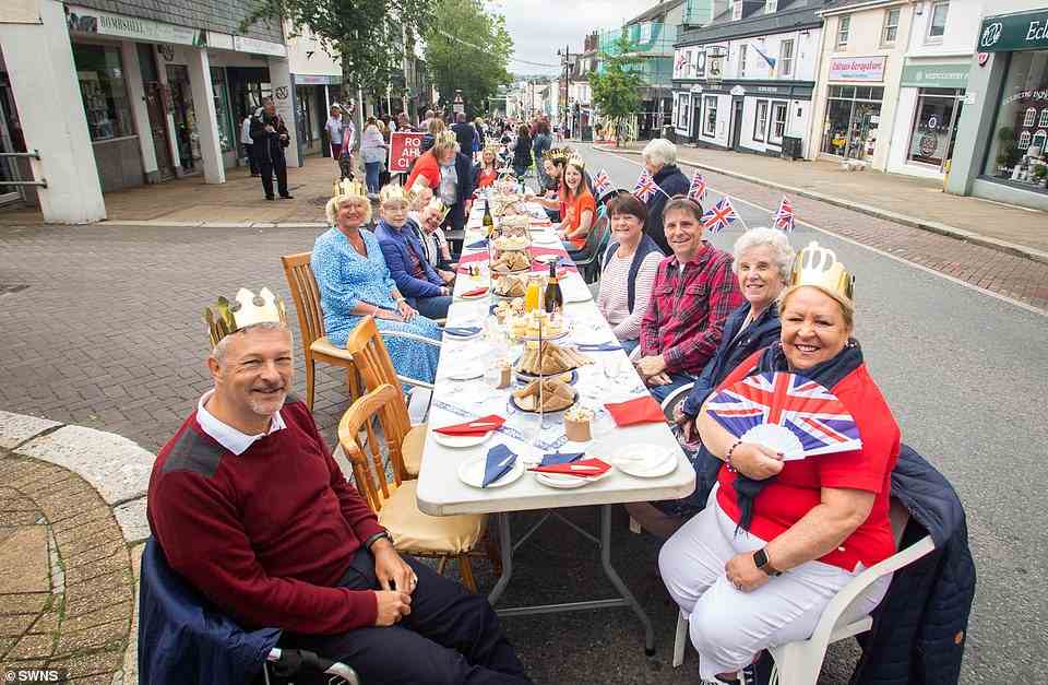 Revellers sitting at a long table on Fore Street, Saltash in Cornwall on June 5, 2022 pose for photos