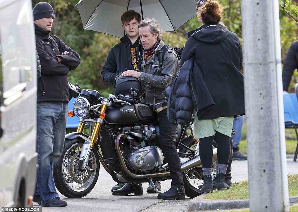 Suave: Guy looked effortlessly cool as he sported a black leather jacket and matching skinny jeans while preparing to film a scene on a motorbike
