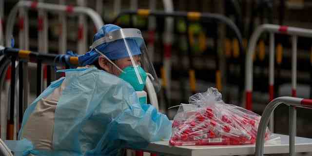 Ein Freiwilliger in Schutzkleidung wartet am Donnerstag, den 9. Juni 2022, auf Bewohner einer Coronavirus-Testeinrichtung in Peking.