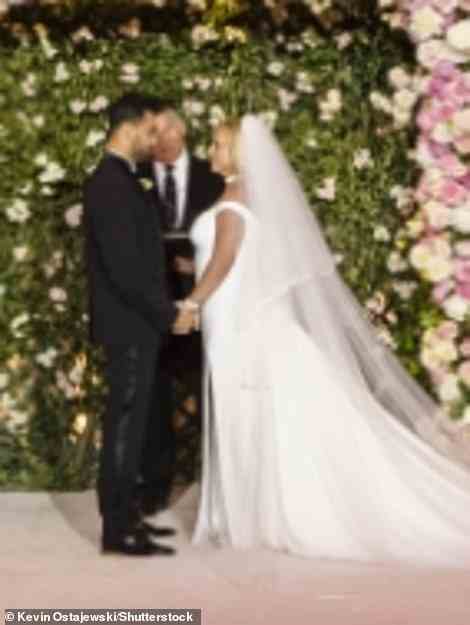 Britney had her blonde hair styled in loose waves that hung down around her shoulders, with her long veil trailing down from her head to the ground behind her as she clasped hands with Sam at the altar