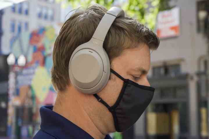 Ein Mann mit Maske und Sony WH 1000XM4 Kopfhörern.
