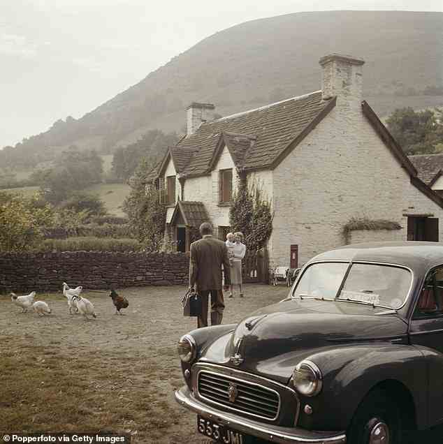View of a country doctor leaving his Morris Minor 1000 car to call on farmer's wife Ivy Wall and child at a farmhouse whilst doing his rounds near Crickhowell in Brecknockshire, Wales in 1959. (Photo by Popperfoto via Getty Images/Getty Images)