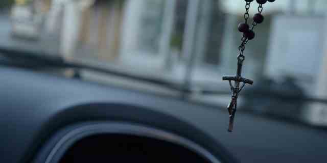 Nahaufnahme eines Kruzifixes, das in einem Auto hängt