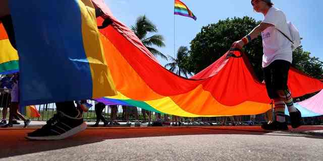 Menschen tragen die Regenbogenfahne, wenn sie am 19. September 2021 in Miami Beach, Florida, an der Miami Beach Pride Parade entlang des Ocean Drive teilnehmen.