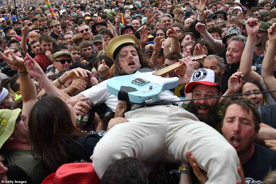 IDLES lead singer Lee Kiernan is pictured crowd surfing with a blue electric guitar in hand during yesterday's packed-out set