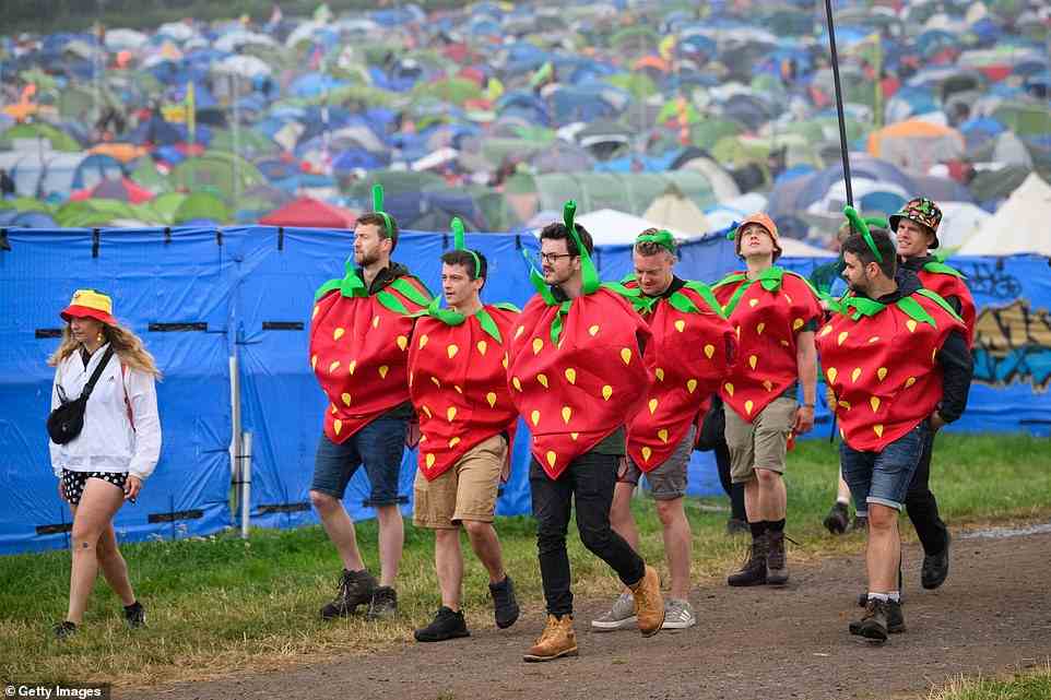 A group of festival-goers dressed as strawberries walk through the site during day three of Glastonbury Festival yesterday
