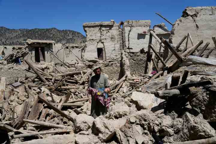 Ein afghanischer Mann trägt sein Kind inmitten der Zerstörung nach dem Erdbeben am Freitag.