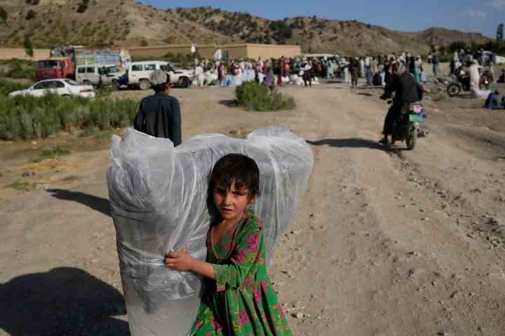 Ein afghanisches Mädchen trägt eine gespendete Matratze.