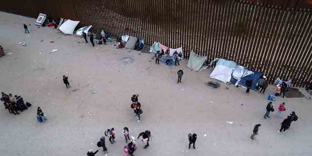 Einwanderer versammeln sich entlang der US-Grenzmauer, nachdem sie am 10. Dezember 2021 in Yuma, Ariz, eine Lücke von Mexiko durchquert haben. 