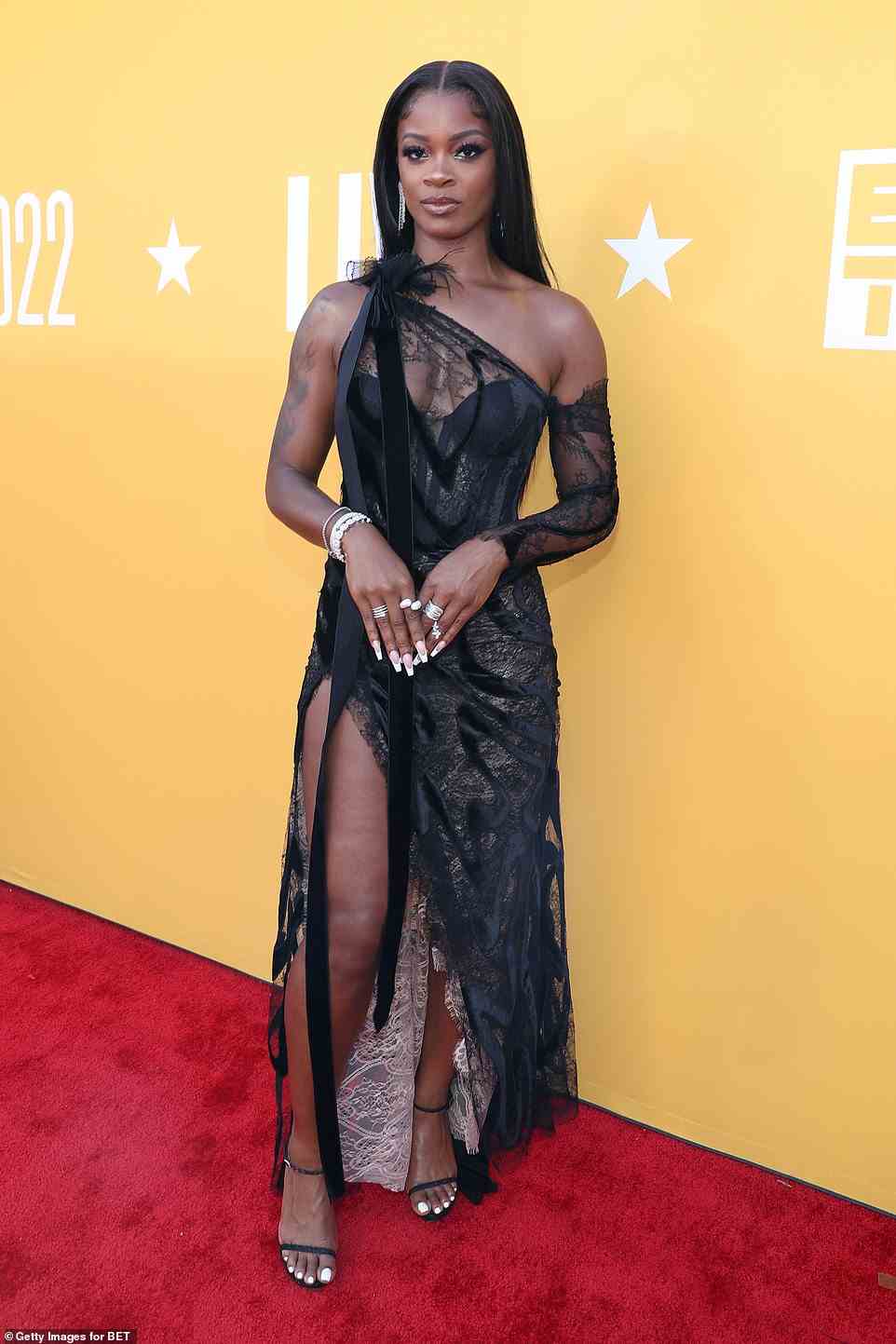 Lace vision: R&B singer Ari Lennox, 31, cut a chic figure in a transparent black lace gown with a bow detail on the shoulder