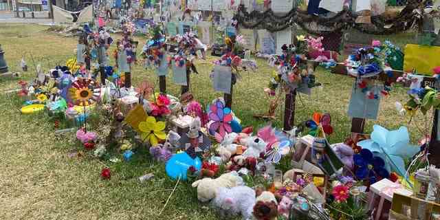 Kreuze mit Blumen sind jedem der Opfer der Massenerschießung von Uvalde gewidmet.  Einen Monat später bringen die Menschen Blumen, ausgestopfte Tiere und Karten zum Denkmal auf dem Stadtplatz. 