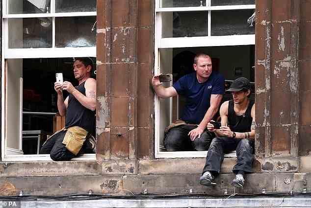 Die Leute beobachteten und fotografierten von einem Fenster aus, als Prinz Charles und Prinzessin Anne zu der Veranstaltung in Edinburgh kamen