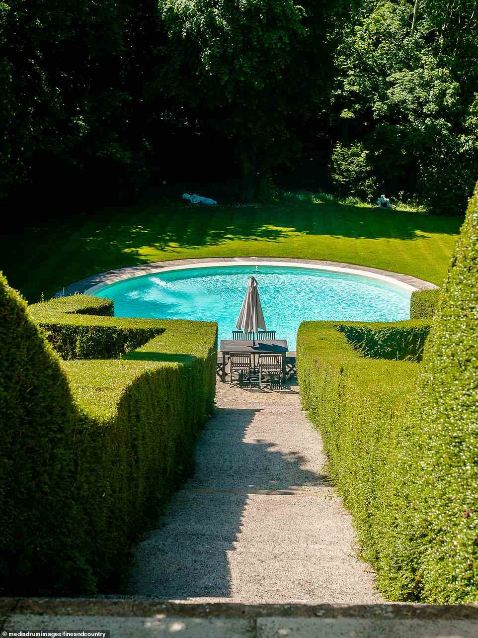 The walkway down to the swimming pool and rear-end of the large garden at High and Over House has a perfectly-prinned hedge which lines the staircase. Also beside the pool is a set of table and chairs to enjoy al-fresco dining on a summer's day