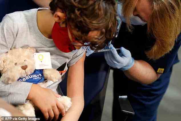 Britische Gesundheitschefs müssen noch die Vorteile der Impfung von unter 5-Jährigen gegen Covid erörtern, wie sich heute herausstellte.  Im Bild: Ein 7-jähriges Kind erhält seine erste Dosis des Impfstoffs in den Beaumont Health-Büros in Southfield, Michigan