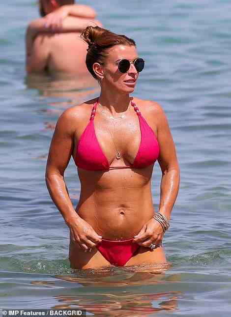 Enjoying a dip: The WAG, 36, looked incredible in her hot pink two piece as she cooled down with an ocean dip during the Balearic beach day with husband Wayne and their pals Lisa and Michael Carrick
