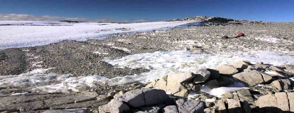 Eine Reihe kleiner Grate im felsigen Gelände zwischen den Felsbrocken im Vordergrund und dem Schnee im Hintergrund auf Inseln, die etwa 100 Kilometer von den Gletschern Pine Island und Thwaites in der Antarktis entfernt sind.