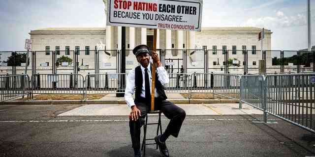 Ein Mann hält ein Schild vor dem Obersten Gerichtshof hoch und fordert die Demonstranten auf, sich nicht zu hassen.