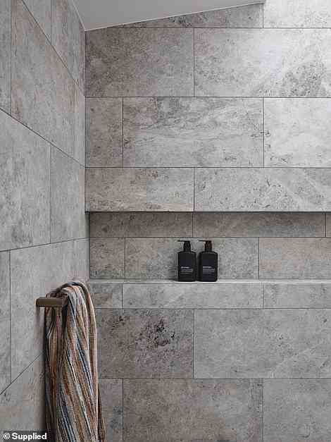 Das Badezimmer ist mit grauem Naturstein geschmückt und wird durch ein Oberlicht über der Dusche erhellt