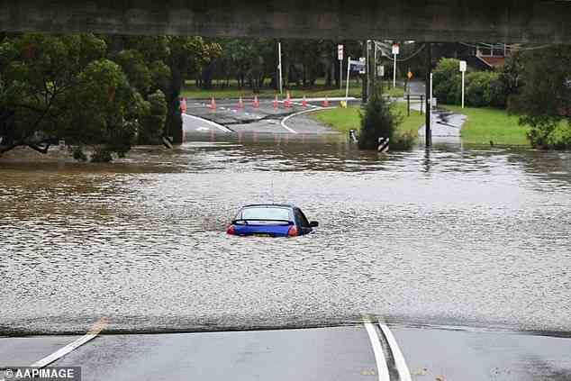 Millions of residents have been told to stay home and put their travel plans on hold as 'life-threatening' storms batter NSW (pictured, an abandoned car trapped in floodwaters at Lansvale in western Sydney on Sunday)
