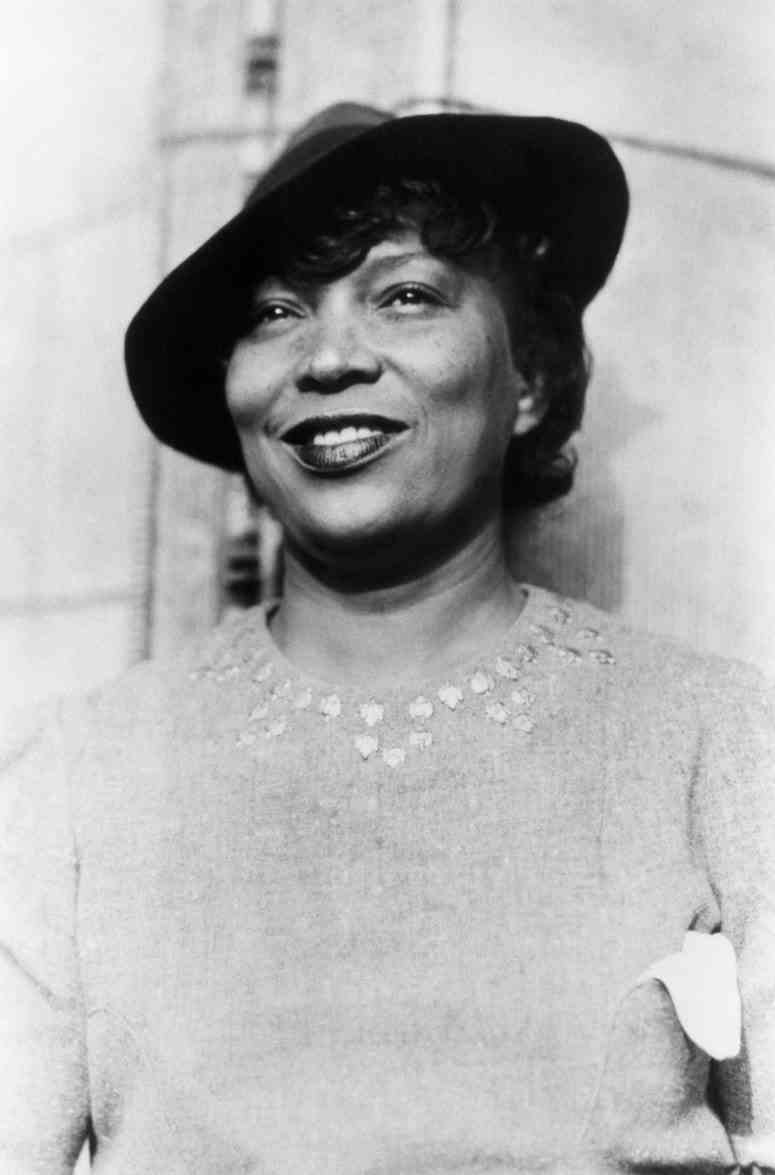 Schwarz-Weiß-Fotografie einer lächelnden Frau in Pullover und Hut